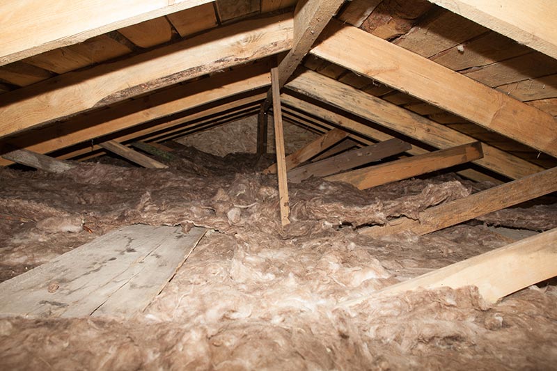 KMF / Mineralwolle Blick in einen attic mit isolierendem Material und sichtbaren Holzstrukturen.
