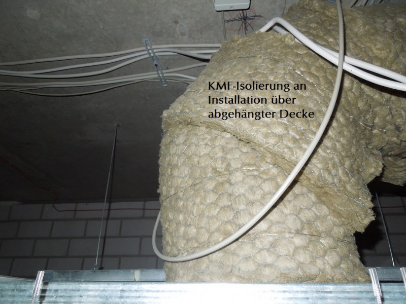 KMF Rohre und Kabel an einer wandmontierten Isolierung in einem technischen Raum.